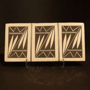 Three-panel floral design on both sides of a black and cream tile