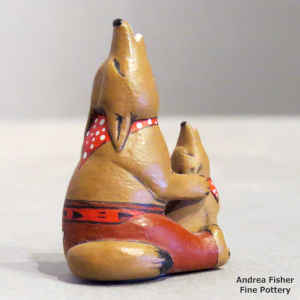 A miniature howling coyote figure with a howling pup