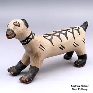 A polychropme dog figure with black paws, black tail, black rings around its eyes, a black snout and a black geometric design on its back