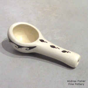 Black water and tadpole symbols on a white ladle