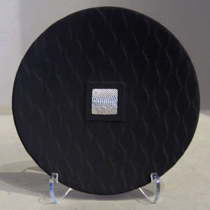 Embedded silver medallion on a grooved black plate