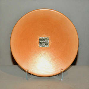 Sterling silver inlay surrounded by a kiva step design on a buff-colored plate