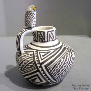 An owl sits on the handle of a black and white jar with a Mimbres-style geometric design