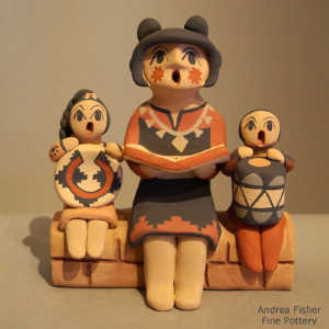 Two children sitting on a wall with a grandmother storyteller