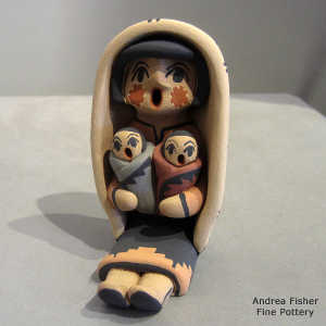 2 children on a grandmother storyteller wearing a manta