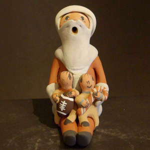 Two children, a footballand a candy cane on a seated Santa Storyteller