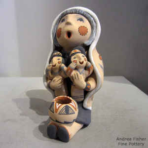 2 children and a pot on a grandmother storyteller wearing a manta