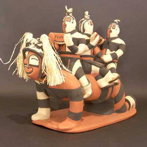 Three children koshares on the back of a kneeling koshare figure