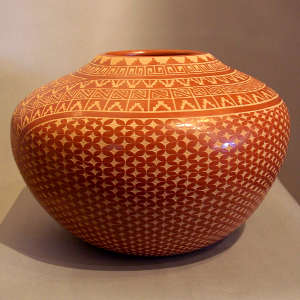 Sgraffito snowflake and geometric design on a polished red jar