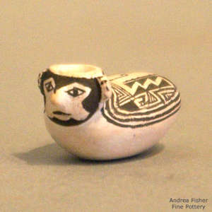 An animal face and geometric design on a miniature black and white jar
