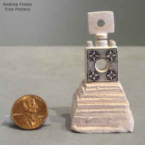An animal face and geometric design on a miniature black and white jar