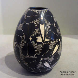 A sgraffito dragonfly design on a black and white jar