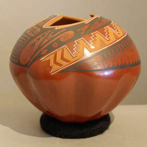 Sgraffito and painted geometric design around an organic opening on a polychrome red jar with a melon-shaped base