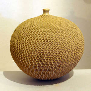 Tiny mouth on a tan pot with corrugated surface