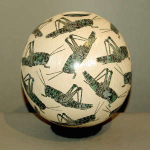 Sgraffito grasshopper design on a green and white jar