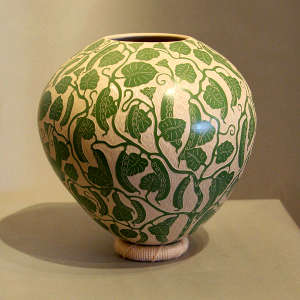 Sgraffito leaf and branch design on a green and white jar