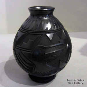 Black jar decorated with a lightly carved and sgraffito hummingbird, flower, dragonfly and geometric  design