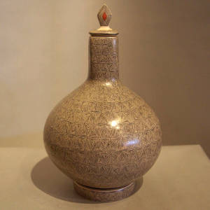 Fine line geometric design on a lidded tall neck jar with a matching stand