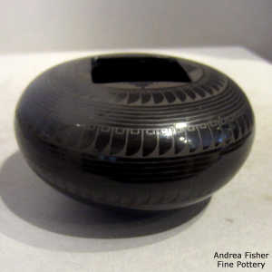 Bands of geometric design pon a black on black jar with a square opening