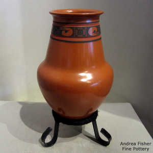 Bands of black geometric design on a red jar with a custom stand