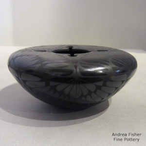 A geometric design on a flat-topped black on black jar with a geometric cut opening