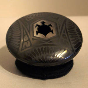 Feather and Paquime designs on a black on black jar with a stylized turtle opening