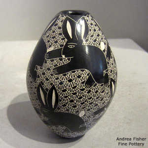 Sgraffito rabbit and mesh design on a black and white jar