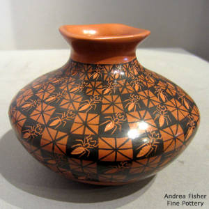 Ant and geometric designs decorate a red and black jar with a square opening