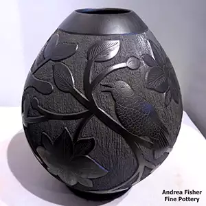 A lightly carved and sgraffito bird, branch and leaf design on a black jar