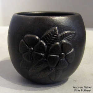 Raised floral design on a black micaceous clay jar