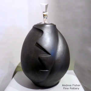 Black micaceous sculptural piece with a sculpted silver lid
