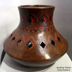 Navajo rug design and diamond cutouts on a tall brown jar