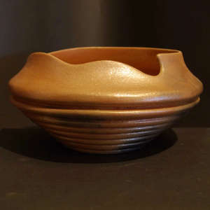 Carved base and an organic opening on an orange micaceous bowl