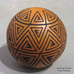 A black geometric design on a miniature golden micaceous seed pot