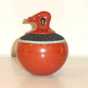 Bear lid and turquoise heishi decoration on a polished red jar