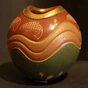 A ring of heishi beads and a sgraffito fish design on a carved red and green jar with a micaceous slip