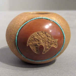 A sgraffito bear and medallion design with inlaid strands of heishe beads on a miniature golden micaceous seed pot