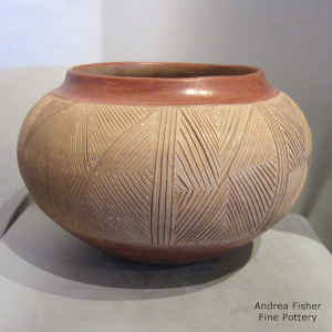 A wide band of lightly carved geometric design with micaceous slip on a red and tan jar