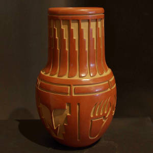 Feather, arrow and geometric designs carved into a tall neck red jar