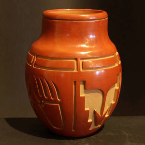 Arrow, bear paw and geometric designs carved into a red jar