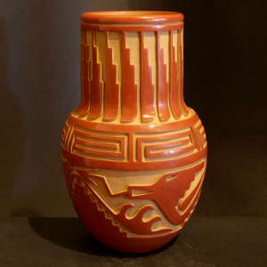 Avanyu, spiral and feather designs carved into a long neck red jar
