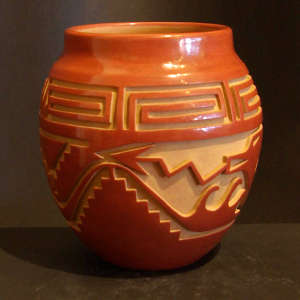 Avanyu, scroll and geometric designs carved into a red jar