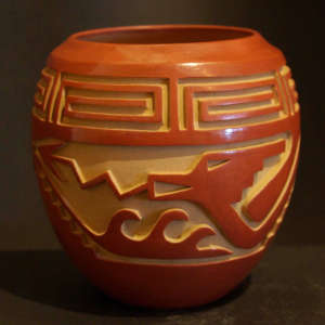 Scroll, avanyu and geometric design carved into a red jar