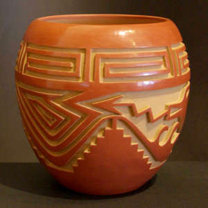 Cloud, avanyu and geometric design carved into a polished red jar