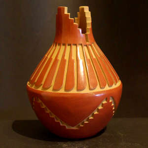 A kiva step and feather design carved into a red jar