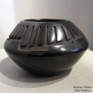 Feather and geometric design carved into a black jar