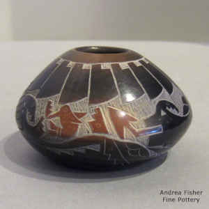 A sgraffito hummingbird, avanyu and geometric design on a miniature black jar with sienna spots