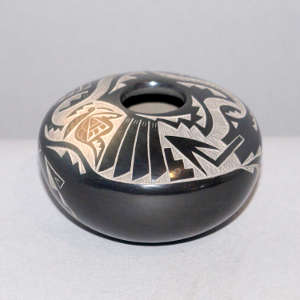 Sgraffito butterfly, feather, avanyu and geometric design on a black seed pot with sienna spots