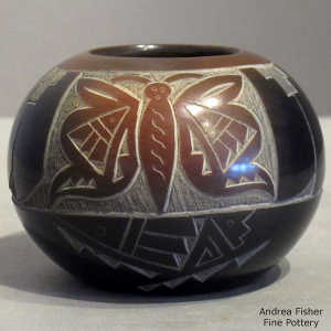 Sienna spot and sgraffito butterfly and geometric design on a black seed pot