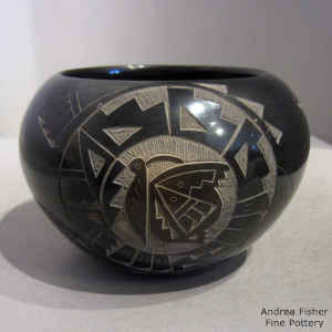 A sgraffito Yei, hummingbird and butterfly medallion with geometric design on a black seed pot with sienna spots